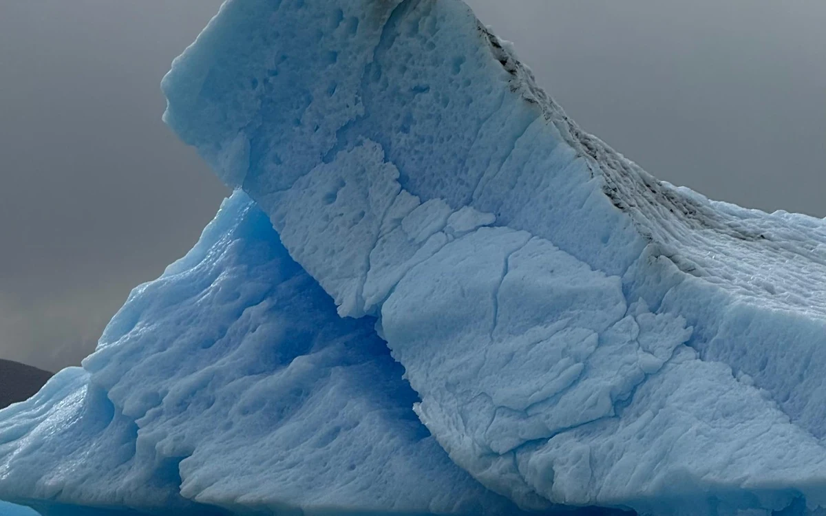 A boat on Lago Argentino in front of the ice wall of the Perito Moreno Glacier