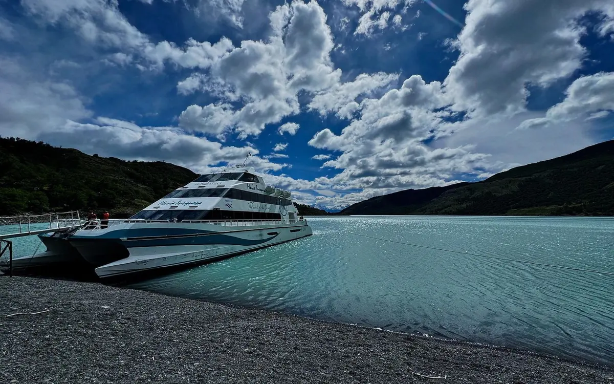 A tour boat in front of the ice wall of the Perito Moreno Glacier with the walkways above